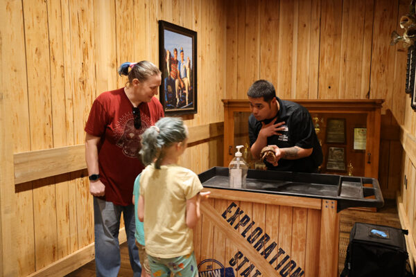 A staff member shows a little girl a turtle.