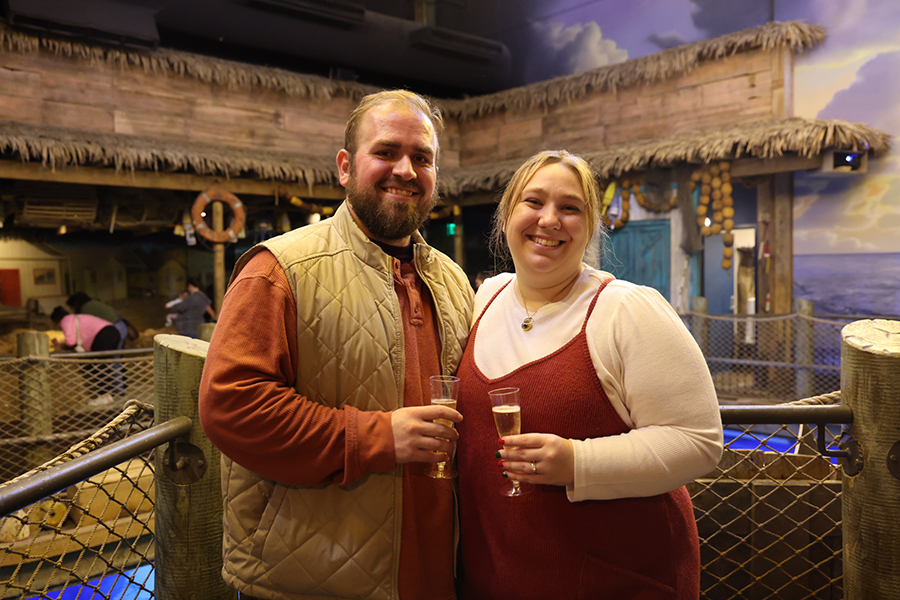 A newly engaged couple stands together at the "Out To Sea Shark Dive" area at Wonders of Wildlife.