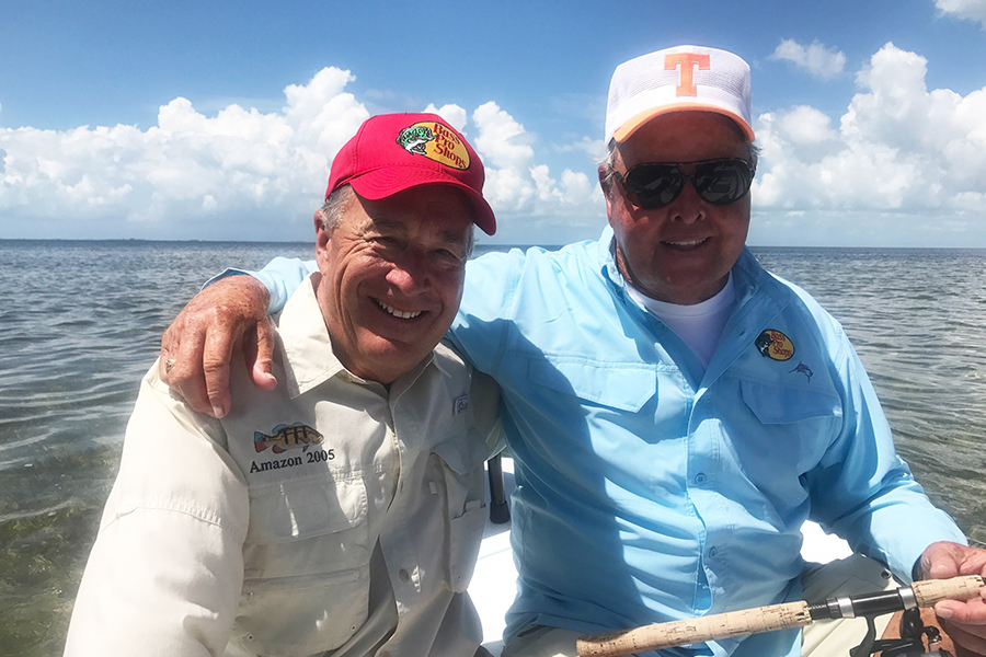 Johnny Morris and Bill Dance pose for the camera with Bill's arm around Johnny while they hold a fishing rod.