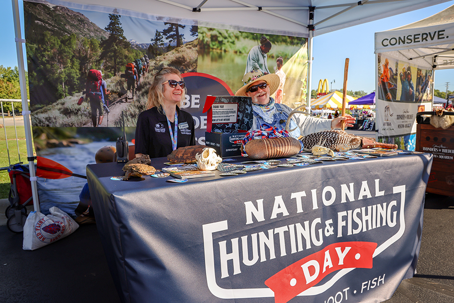 Staff and volunteers smile behind the National Hunting & Fishing Day table.