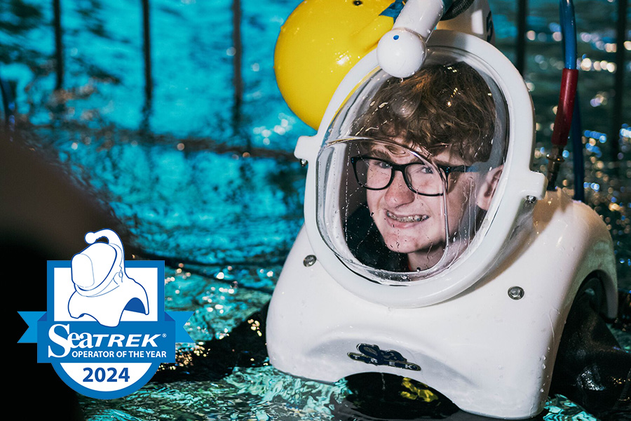 A young boy wearing glasses smiles through his dive helmet as he wades in the shake dive tank at Wonders of Wildlife.