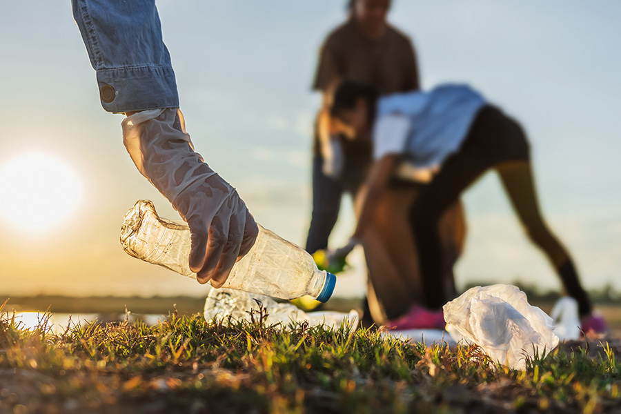 Several people picking up trash and debris on in a field.